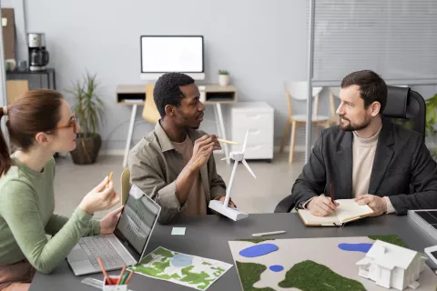 3 personnes qui discutent autour d'une table de bureau