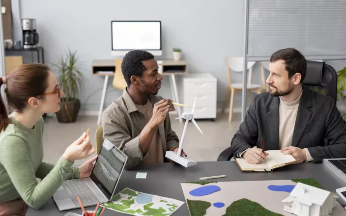 3 personnes qui discutent autour d'une table de bureau 