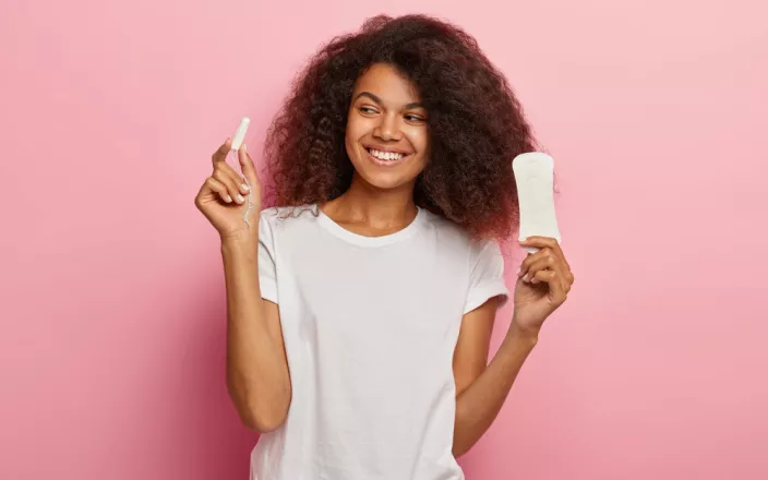 Femme d'origine africaine tenant dans ses mains un tampon et une service hygiénique