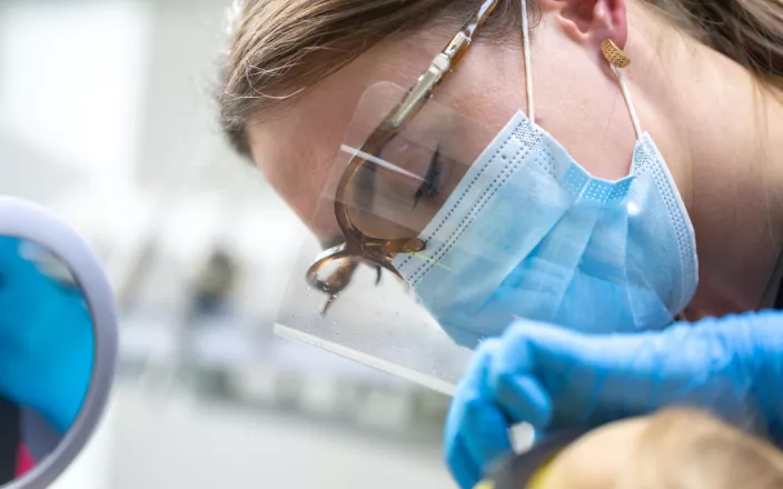 Femme portant un masque et des lunettes chirurgicaux en train d'opérer