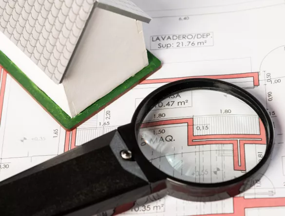 Loupe et maquette d'une maison sur une cartographie