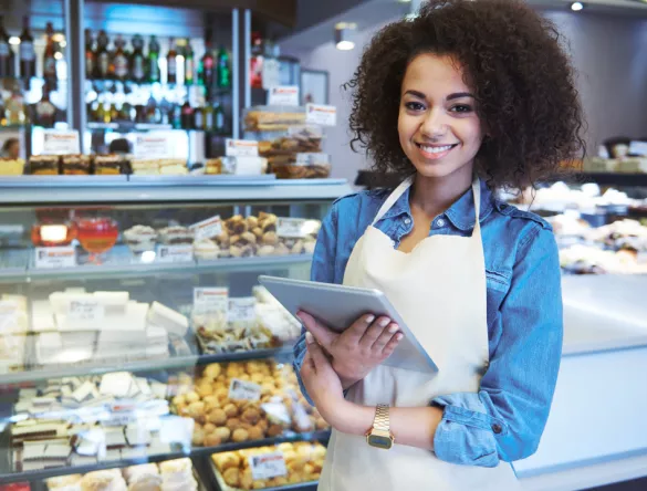 Jeune femme de type métisse portant un tablier blanc dans son commerce d'alimentation