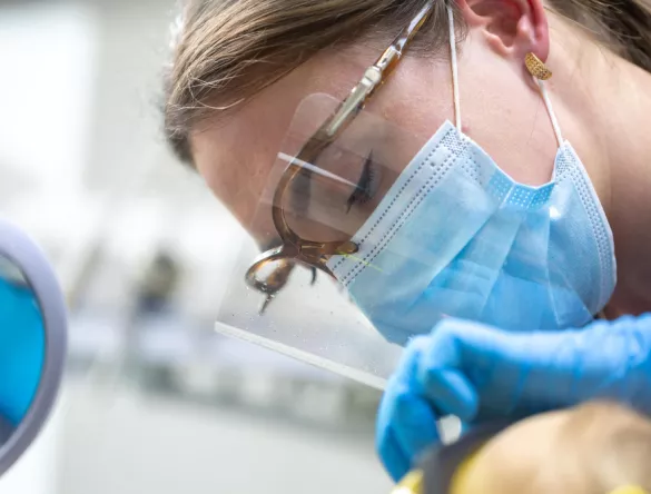 Femme portant un masque et des lunettes chirurgicaux en train d'opérer